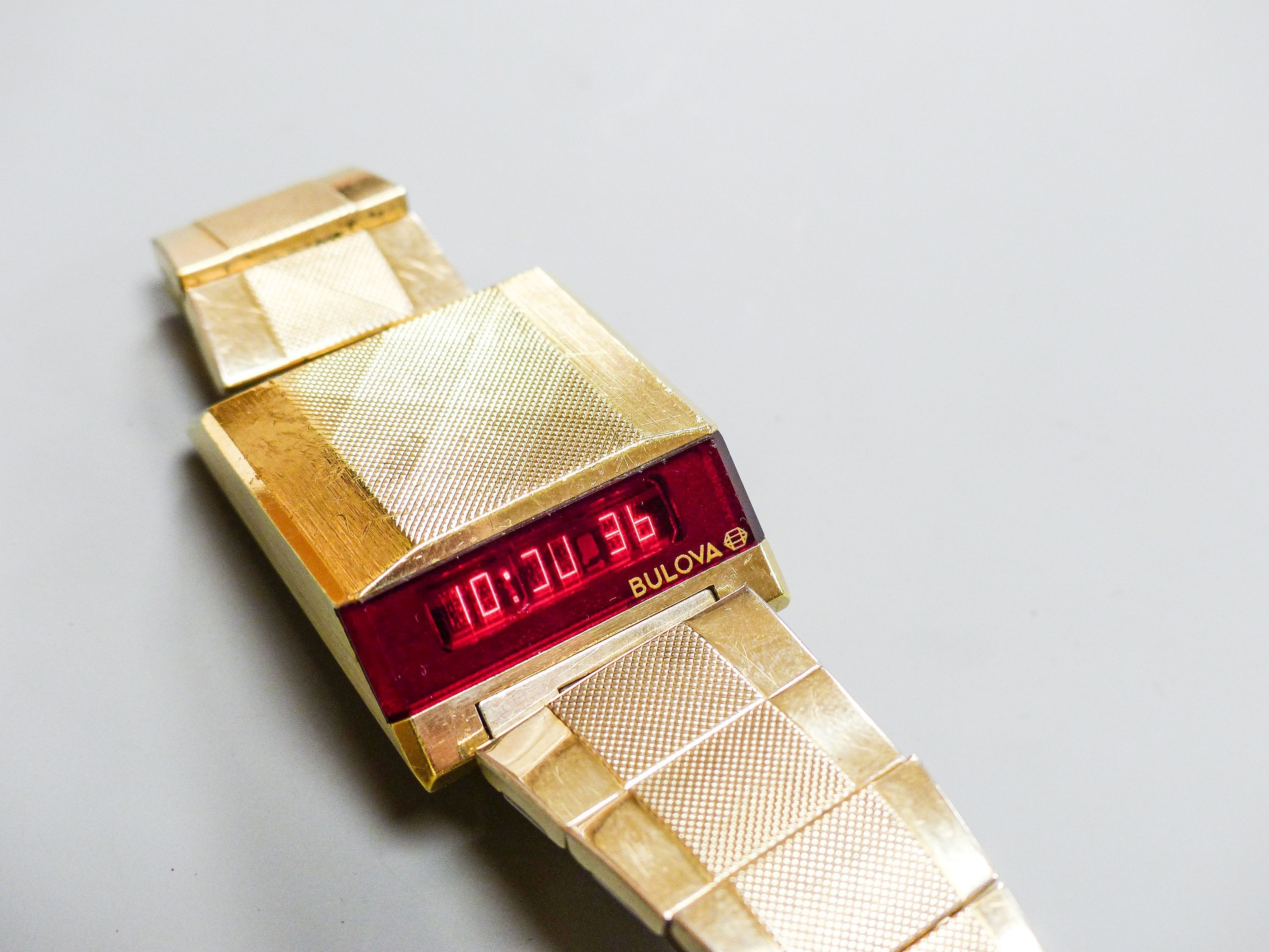 A gentleman's steel and gilt base metal Bulova digital wrist watch, on Bulova bracelet, case diameter 30mm (a.f.).